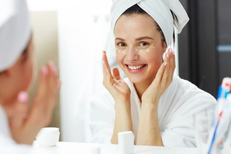 Mujer joven aplicando producto para realizar su hidratación facial en casa