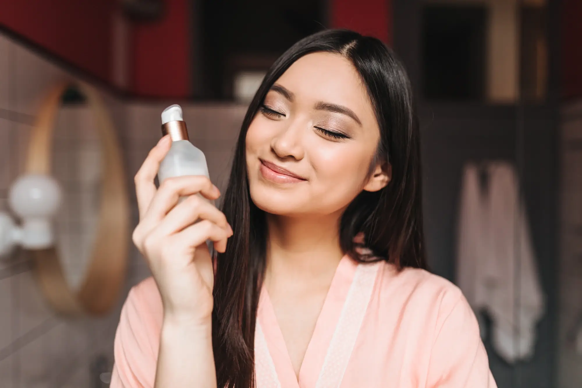 Mujer sonríe con los ojos cerrados mientras sostiene un producto de cuidado facial formulado con ácido hipocloroso