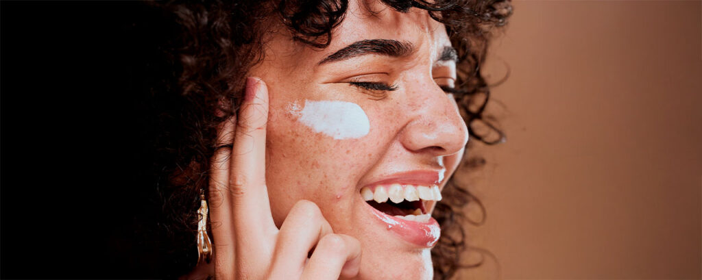 Mujer con piel radiante aplicando crema hidratante como parte de su rutina de cuidado de la piel