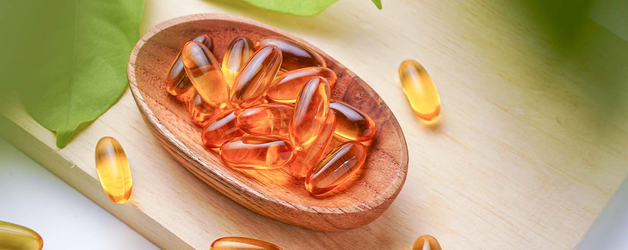 Cápsulas de Vitamina E en un recipiente de madera, ideales para el cuidado de la piel del rostro