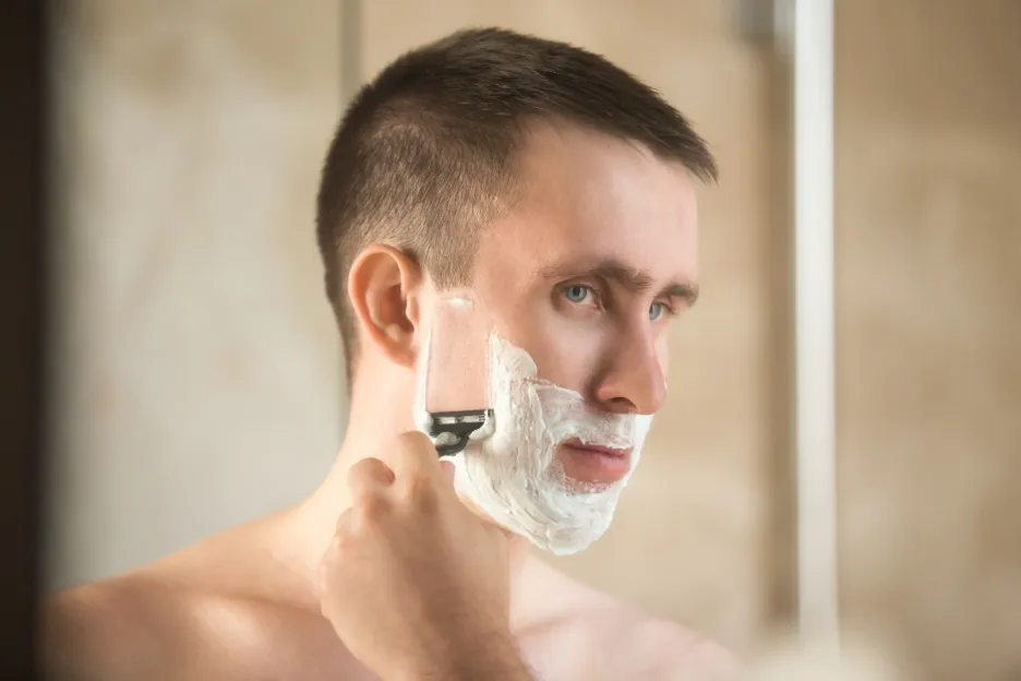 Hombre afeitándose el rostro en una rutina diaria.