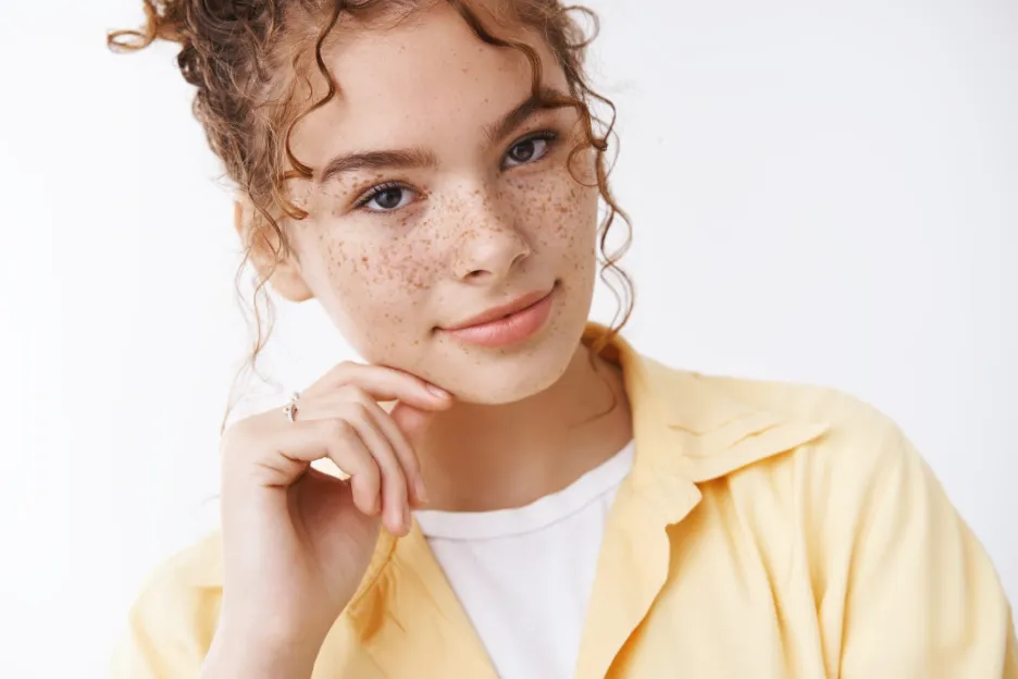 Mujer joven con pecas visibles en las mejillas y la nariz